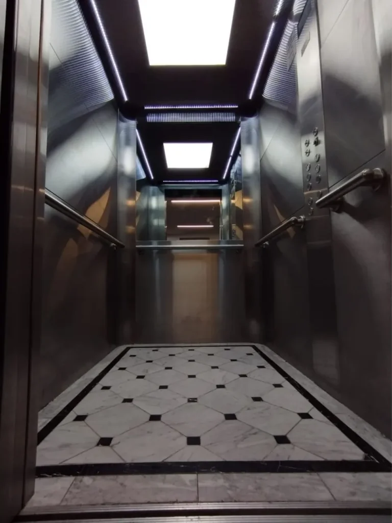 Interior de cabina de ascensor con piso de mármol